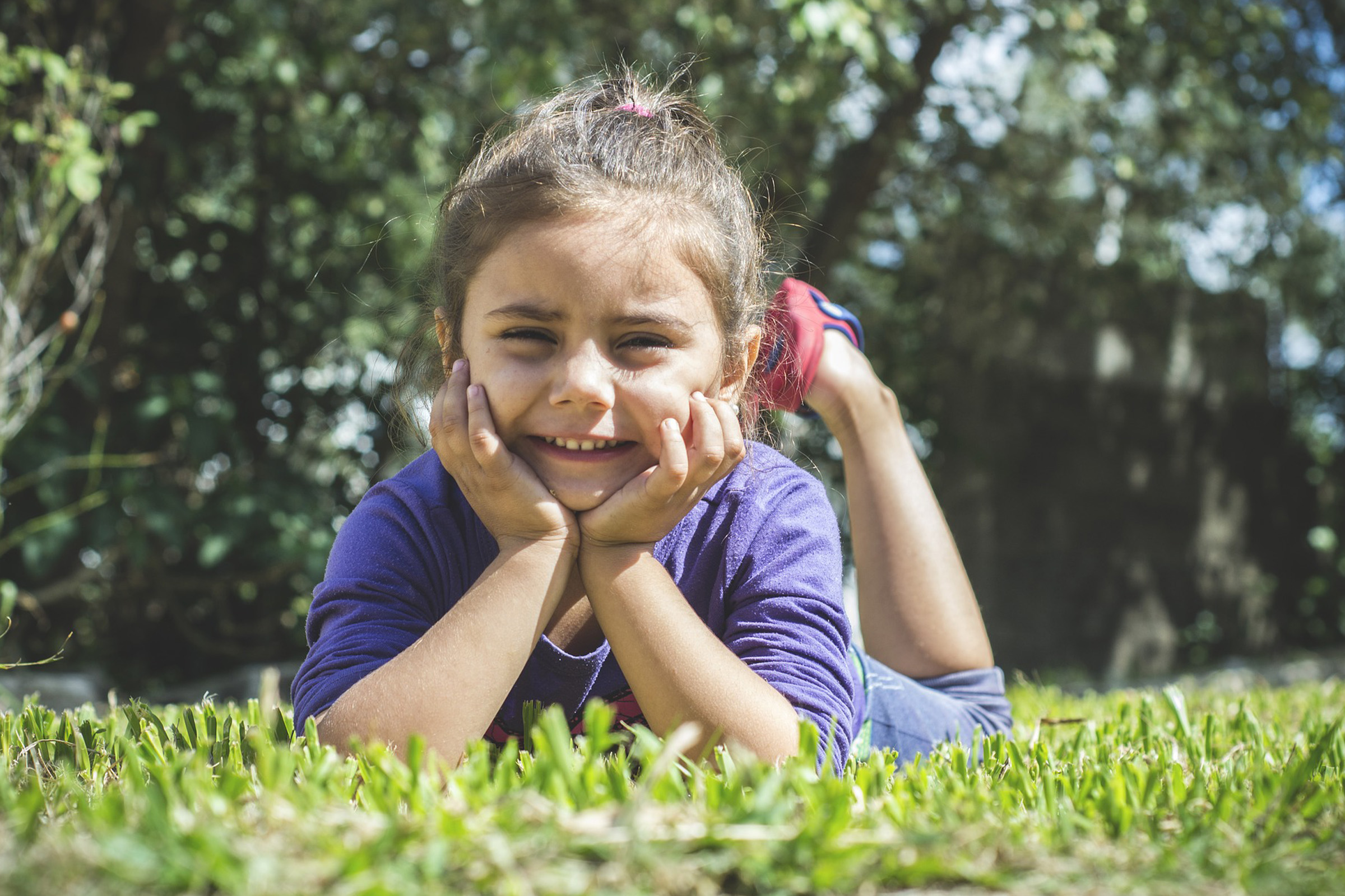 photo of young girl sitting in grass